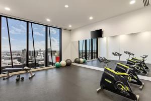 einen Fitnessraum mit Laufbändern, Trainingsgeräten und Fenstern in der Unterkunft Quick Aces Premium in Melbourne