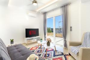 a living room with a couch and a tv at Elysian Rose Residence in Rethymno Town