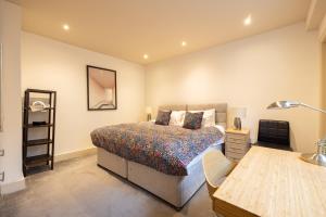 a bedroom with a bed and a desk with a lamp at Niru Experience Hidden Gem in Chelsea in London