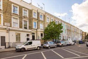 uma fila de carros estacionados em frente a um edifício em Niru Experience Hidden Gem in Chelsea em Londres