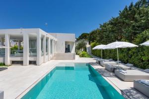 a villa with a swimming pool with chairs and umbrellas at B&B Villa EraGea in Matino