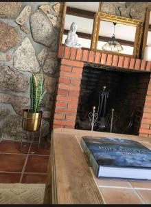 Habitación con chimenea de ladrillo y mesa con un libro. en Villa Amaris en Santa Maria del Tietar