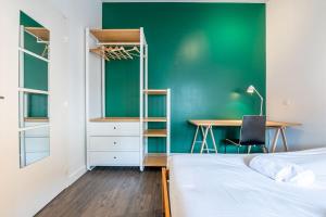 a bedroom with a green wall and a desk and a bed at Entre Bastille et hyper-centre: lave-linge - fibre in Grenoble