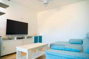 uma sala de estar com um sofá azul e uma televisão em Hostal Paraiso del Mar em Torre del Mar