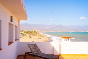 a chair sitting on a balcony overlooking a beach at Hostal Paraiso del Mar in Torre del Mar
