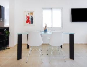 a glass table with white chairs in a room at The Adam's by HolyGuest in Tel Aviv