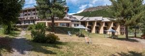 un edificio con sedie e ombrelloni di fronte di VVF Serre Chevalier Briançon a Le Monêtier-les-Bains