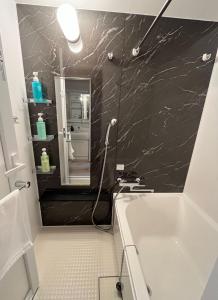 a bathroom with a white tub and a black wall at Seiryu Tsutenkaku in Osaka