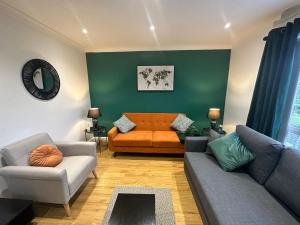 a living room with an orange couch and a green wall at Stylish townhouse-Central location-Great discoun s in Milton Keynes