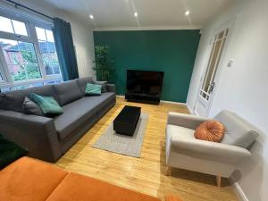 ein Wohnzimmer mit Sofa und Fernseher in der Unterkunft Stylish townhouse-Sleeps 9-Free parking in Milton Keynes