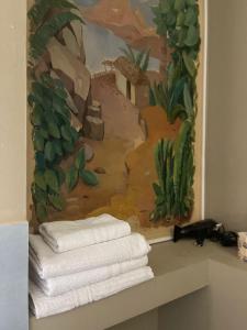 una pared con toallas en un estante con una pintura en B&B Piazza Duomo al 55, en Voghera