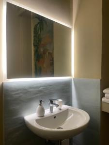 lavabo blanco en el baño con espejo en B&B Piazza Duomo al 55, en Voghera