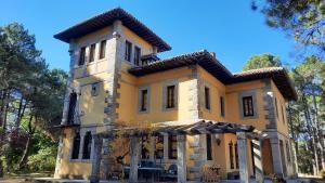 a large yellow building with a tower at QUINTA ARENlLLAS Palacete en una finca privada de 7 hectáreas de pinar in Navalperal de Pinares