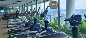 une salle de sport avec une rangée de tapis de course devant une fenêtre dans l'établissement The Colony Skyline Suites KLCC, à Kuala Lumpur