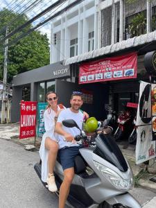 un homme et une femme voyageant sur un scooter dans l'établissement Smile Capsule Hostel, à Chiang Mai