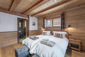 a bedroom with a large white bed and a wooden wall at Chalet Carnauba in Châtel