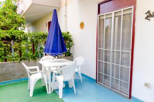 eine Terrasse mit einem weißen Tisch und Stühlen sowie einem blauen Sonnenschirm in der Unterkunft Appartamento Akesines in Trappitello