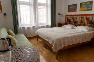 1 dormitorio con 1 cama, 1 sofá y 2 ventanas en Kolory Guest House, en Cracovia