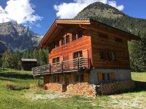 a wooden house in a field with a mountain at Chalet with style in the beautiful Val Ferret in Praz-de-Fort