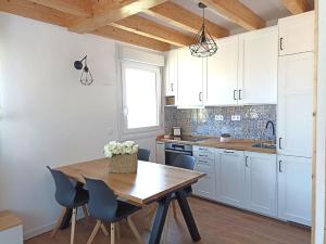 a kitchen with white cabinets and a wooden table and chairs at EL PALOMAR DE GÜERRES in Colunga