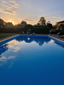 a large blue swimming pool with a sunset in the background at Casale Dolci Dimore in Massa Martana