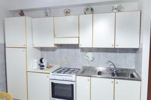 una cocina con armarios blancos y fregadero en Appartamento Akesines, en Trappitello