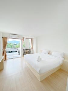 a white bedroom with a large bed and a balcony at Tanatnan Hotel in Ranong