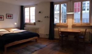 a bedroom with a bed and a table and windows at Ferienwohnung Scheffelhaus in Gengenbach