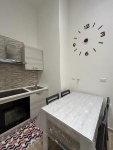 eine Küche mit einem Tisch und einer Uhr an der Wand in der Unterkunft CASA VACANZE IL FONDACO in Giovinazzo