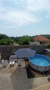 ein Sonnenschirm und Stühle neben einem Pool in der Unterkunft Old house Djurovic in Herceg-Novi