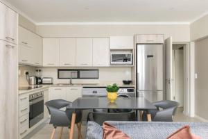 a kitchen with white cabinets and a black table and chairs at Lux 2bed 20Mb WiFi on Keyes artmile 2km 2 Gautrain in Johannesburg
