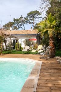 una piscina con sillas y una casa en Landaise le lagunak avec piscine chauffée à 900 M de la plage, en Labenne
