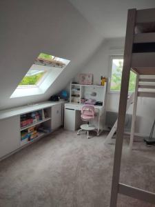 a attic room with a desk and a window at Maison individuelle 3 chambres in Pleudihen-sur-Rance