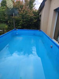 a blue swimming pool in front of a house at Maison individuelle 3 chambres in Pleudihen-sur-Rance