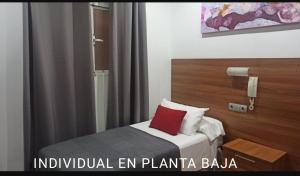 um quarto de hotel com uma cama com uma almofada vermelha em Hostal San Francisco em Cádiz