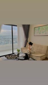 a woman sitting on a couch in a living room at Căn hộ khách sạn gần biển TMS Luxury Quy Nhơn - Hanna House in Quy Nhon