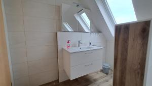 La salle de bains blanche est pourvue d'un lavabo et d'une fenêtre. dans l'établissement Ferienwohnung am Altmühlsee, à Gunzenhausen