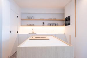 una cucina con armadi bianchi e lavandino di Luxury Design Apartment with free private parking a Ostenda