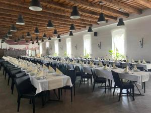un gran salón de banquetes con mesas y sillas blancas en Vadkert Major en Sárvár