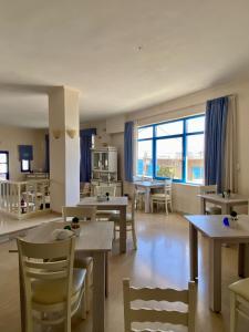 uma sala de estar com mesas e cadeiras e uma grande janela em Pallada Hotel em Agía Galíni
