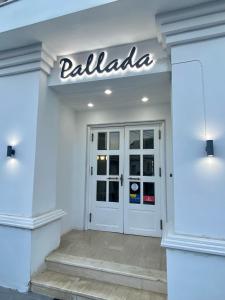 uma frente de uma loja branca com um sinal por cima da porta em Pallada Hotel em Agía Galíni