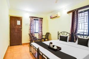 a bedroom with two beds and chairs and windows at Hotel Joaquim Near Baga Beach in Baga