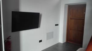 een flatscreen-tv aan een muur naast een deur bij Vivienda Vacacional San Roque, 30 in Garachico