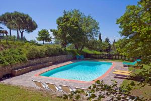 una piscina con sedie, una recinzione e alberi di Podere Argena a Lucignano