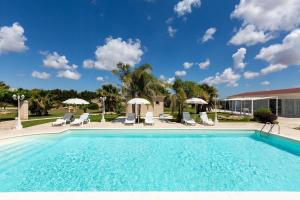 a large swimming pool with chairs and umbrellas at Tenuta Donna Caterina by BarbarHouse in Mesagne