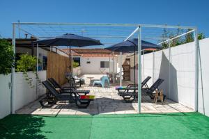 grupa krzeseł i parasoli na patio w obiekcie Casa dos Marianinhos w mieście Elvas