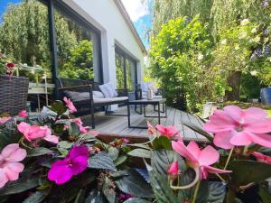 eine Terrasse mit rosa Blumen vor einem Haus in der Unterkunft Le Tonneau insolite du Souffle du Saule in Buhl-Lorraine