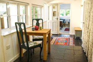 ein Esszimmer mit einem Tisch, Stühlen und Fenstern in der Unterkunft Cosy Cottage with Log Burner, Large Garden, Dog Friendly! in Monks Eleigh