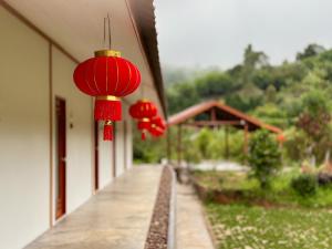 a row of red lanterns hanging off the side of a building at Baan Daeng Resort บ้านรักไทย in Ban Rak Thai