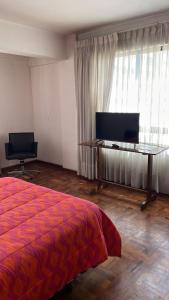 Dormitorio con cama, escritorio y TV en Edificio frente Club Tenis., en Cochabamba